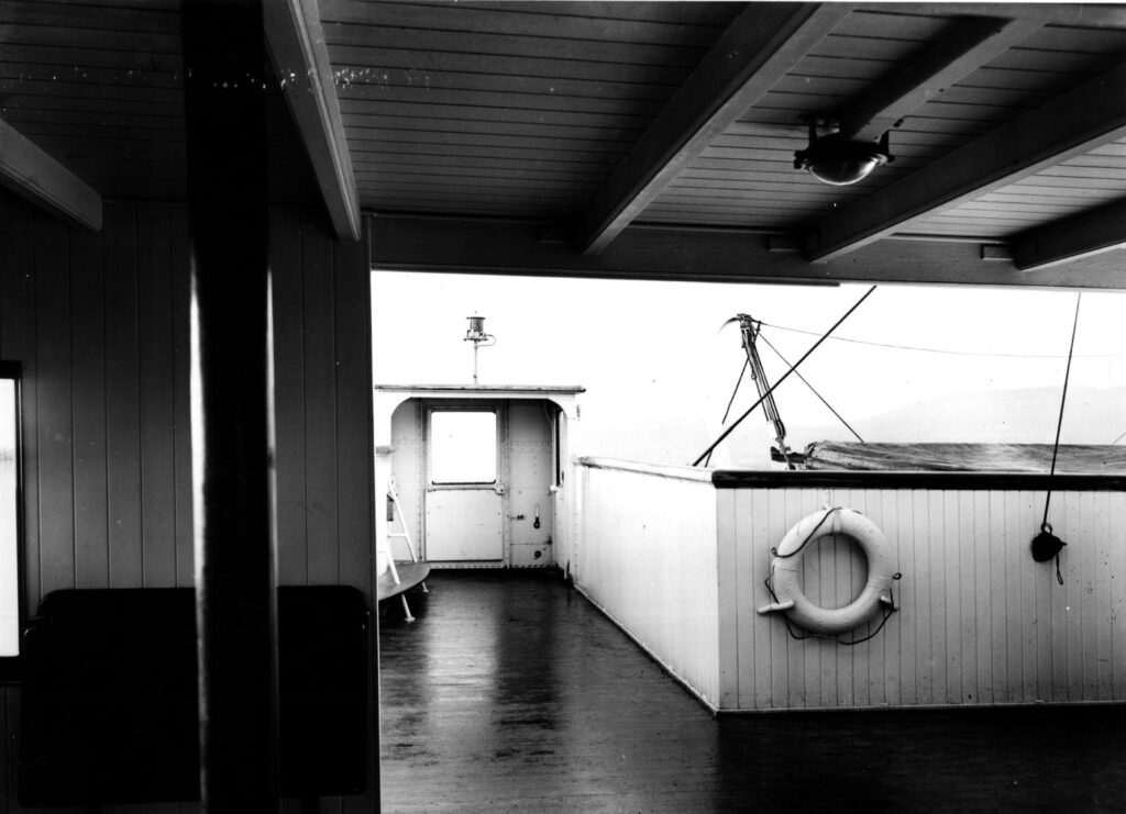 A view of Olympic’s bridge wing and wing cab. Again, the fold-down chart table can be seen in the foreground against the bridge wall. The wing cab clearly shows the large signaling lamp atop it. To the right of the cab near the bottom is the small hatch that would’ve allowed access to the sidelight.